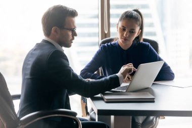 Businessman and businesswoman talking in boardroom at meeting.