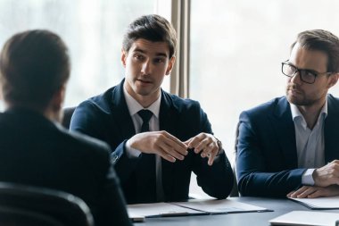 Confident businessman discuss project sit at table in boardroom.