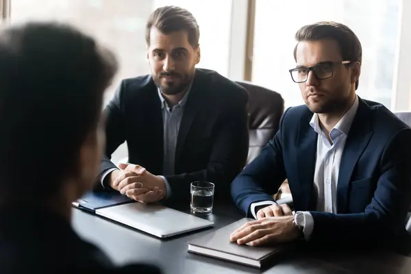 Twee serieuze Hr zakenmannen luisteren mannelijke sollicitant tijdens het werk interview. — Stockfoto