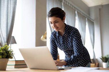 Smiling Indian woman working on laptop at home