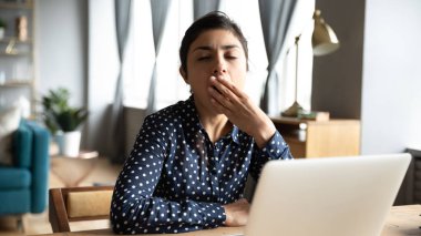 Tired ethnic woman yawn sigh at workplace