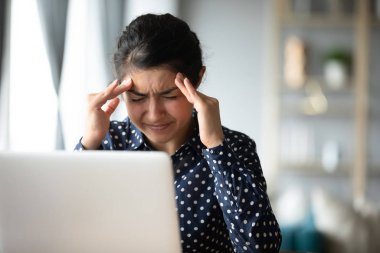 Tired Indian girl suffer from migraine at workplace