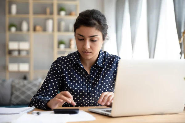 Focused ethnic woman paying bills online on laptop — Stock Photo, Image