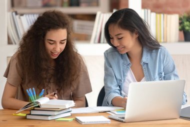 Two diverse Asian and Caucasian girls students studying together
