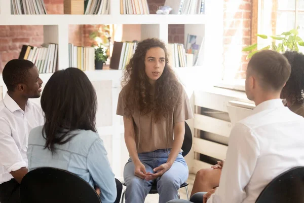 Woman speaking at group counselling therapy session sitting in circle