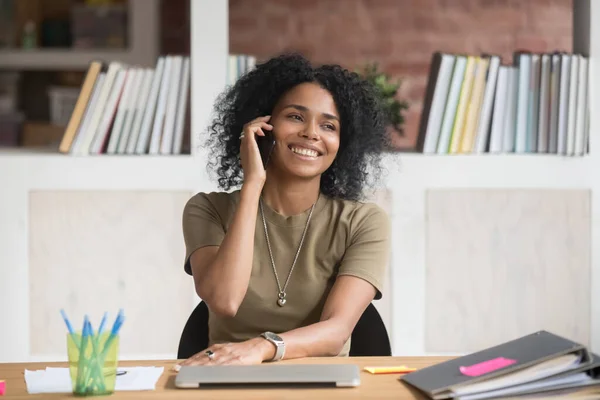 Sonriente mujer de negocios afroamericana hablando por teléfono en el trabajo —  Fotos de Stock