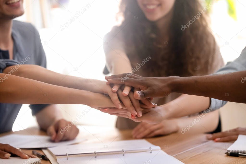 Close up smiling diverse students or employees putting hands together