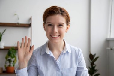 Head shot portrait of attractive smiling businesswoman waving hand