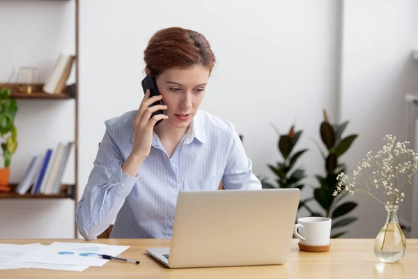 Ocupada empresaria hablando por teléfono, usando laptop, consultando cliente — Foto de Stock