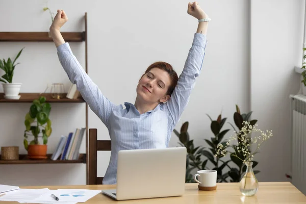 Satisfied businesswoman stretching at workplace after finished work