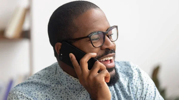 Empresário afro-americano animado falando ao telefone no local de trabalho — Fotografia de Stock