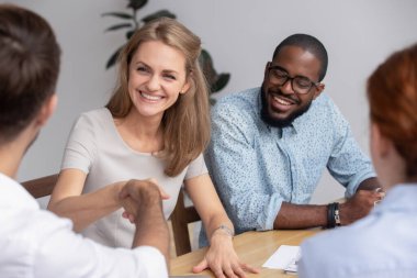 Smiling businesswoman shaking hand of business partner at meeting