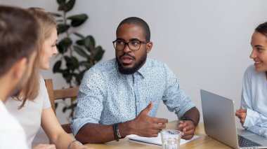 African American business coach holding briefing with employees in boardroom