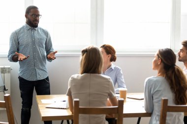 African American coach holding briefing with employees in boardroom