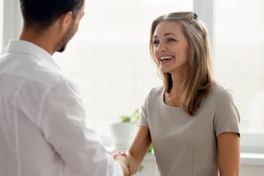 Boss shaking hand of smiling businesswoman, congratulating with promotion