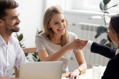 Excited businesswoman shaking hand of business partner at successful meeting