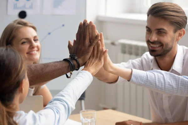 Close up diverse colleagues giving high five, celebrate great results