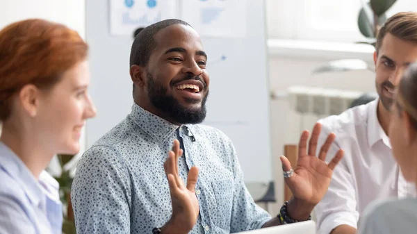 Sonriente hombre de negocios afroamericano charlando con colegas en la sala de juntas —  Fotos de Stock
