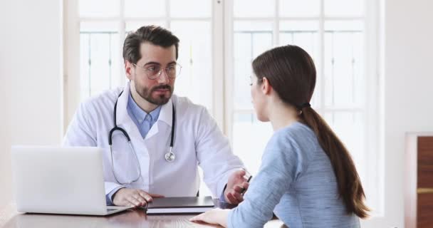 Профессиональный врач мужского пола консультирует молодую женщину пациента во время медицинского визита — стоковое видео