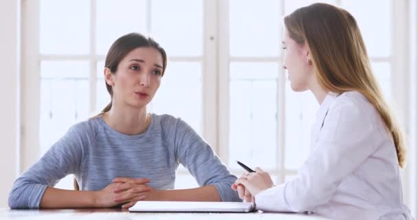 Young woman patient talking to female doctor at medical checkup — Stockvideo