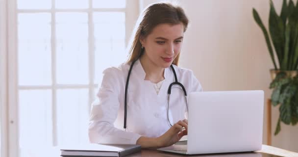 Young woman doctor wear white coat using laptop computer — Stockvideo