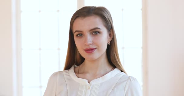 Confident smiling pretty millennial woman looking at camera posing indoors — Stock videók