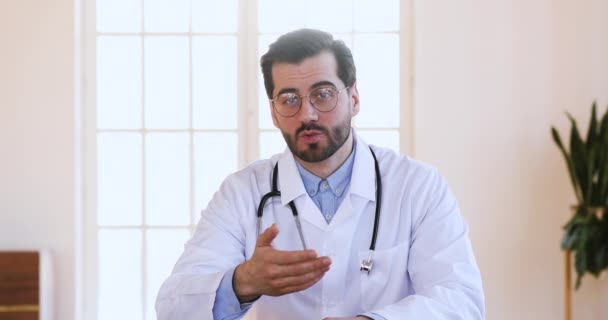Профессиональный врач мужского пола смотрит в камеру и делает видеозвонок — стоковое видео