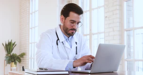 El médico profesional masculino usa abrigo médico usando computadora portátil — Vídeo de stock