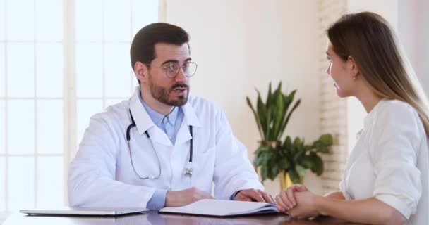 Улыбающийся врач и женщина пожимают руку пациенту во время медицинской консультации — стоковое видео