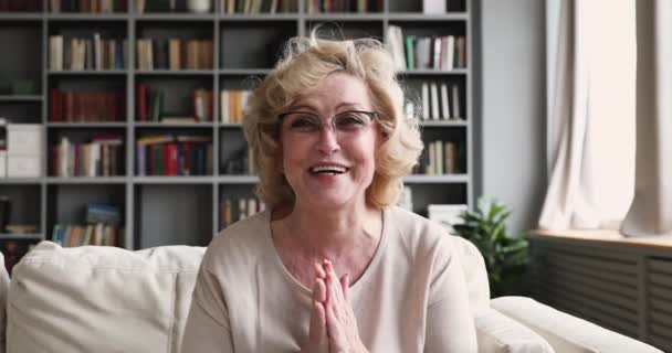 Cheerful older woman talking to camera video calling at home — Stock videók