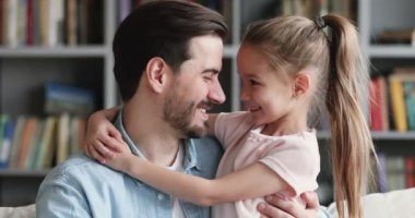 Happy dad and cute kid daughter cuddling looking at camera