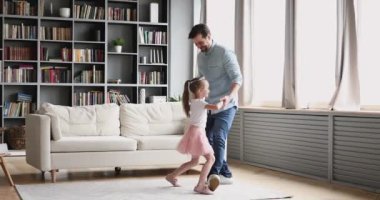 Affectionate dad dancing with child daughter princess in living room