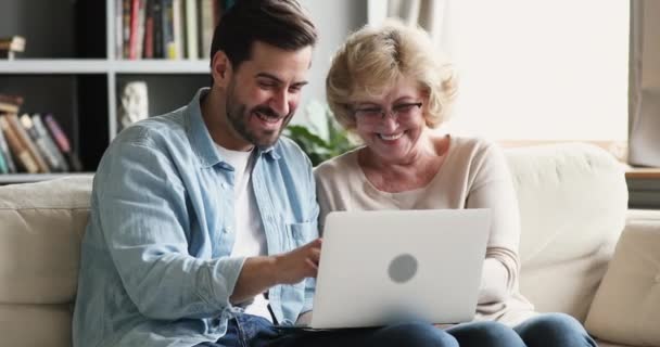 Счастливая зрелая мать и маленький сын смеются, используя ноутбук вместе — стоковое видео