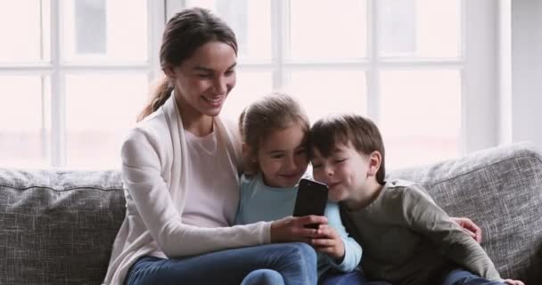 Cheerful mum showing funny mobile app having fun with kids — Stock videók