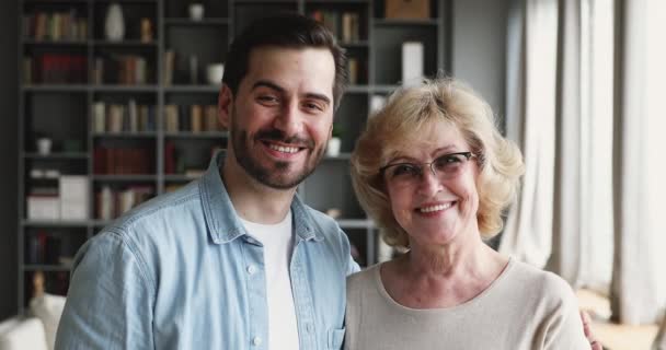 Happy older mother and young son bonding looking at camera — Stok video