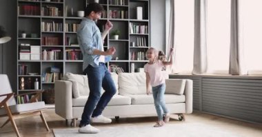 Active cheerful dad dancing having fun with kid at home