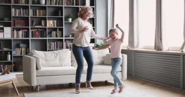 Small girl granddaughter dancing with old grandma in living room