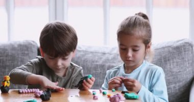Two cute children siblings making toys of playdough at home