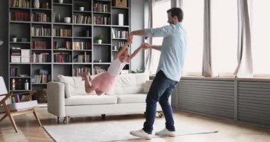 Loving father having fun spinning with child daughter at home