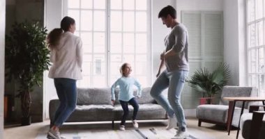 Happy young couple dancing with child daughter in living room