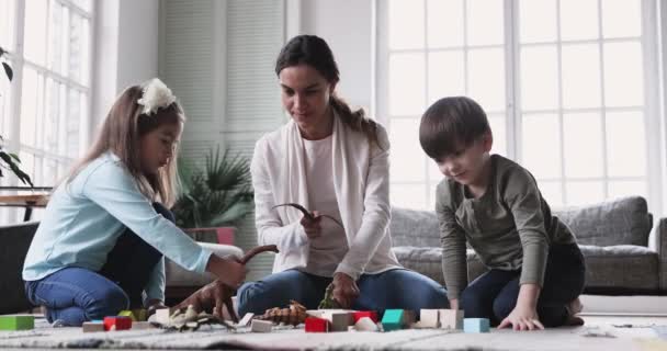 Jovem mãe babá brincando com crianças no chão da sala de estar — Vídeo de Stock