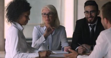 Confident multiracial older and younger business people discussing partnership conditions.