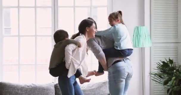 Pais ativos brincando com crianças dão às crianças passeio de piggyback — Vídeo de Stock