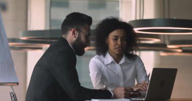 Concentrated multiracial coworkers discussing business project details.