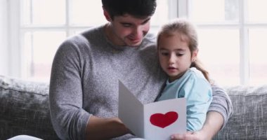 Cute adorable small child daughter reading postcard on fathers day