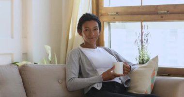 Happy young african american girl holding mug of hot coffee.