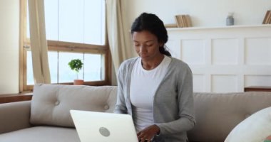 Focused young african ethnicity woman typing message on computer.