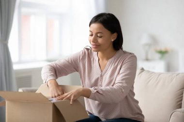Heyecanlı çift ırklı kadın posta paketini online sipariş ile açıyor.