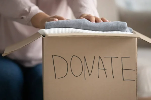 Female volunteer put clothes into cardboard donation box — Stock Photo, Image