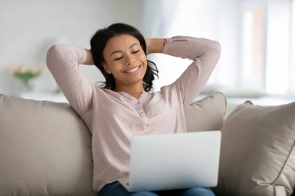 Mulher biracial feliz relaxar no sofá usando laptop — Fotografia de Stock